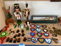 Various vintage Christmas ornaments and decorations laid out on a surface, including wooden hearts, wooden soldiers, a brass angel, shaped candle holders, and a boxed Christmas tree topper.
