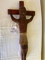 Full view of the hand-carved wooden crucifix sculpture showing the figure of Jesus with arms raised and cross behind.