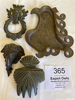 Four vintage decorative items: metal door knocker, ram head sculpture, brass bird tray, carved beach stone.
