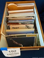 Top-down view of brown storage box filled with assorted vintage postcards organized in sections.