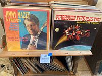 Photo of front row vinyl album covers including Jimmy Mazzy & Friends and Firehouse Five Plus Two Around The World on a wooden rack with many other albums behind them
