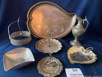 Photo showing seven vintage silver plate and pewter serveware items including trays, bowls, a condiment holder, and a pewter pitcher.