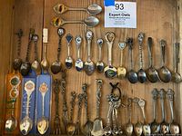 Full display of 29 vintage souvenir spoons with varied designs and three spoons in original Tasle branded packaging.