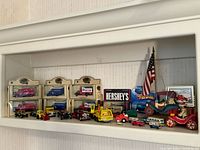 Full view of shelf displaying vintage toy model cars including boxed and loose cars, variety of colors and brands.