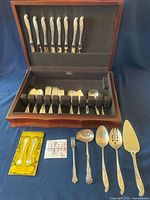 Entire flatware set in open wooden box with felt liners