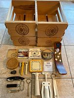 Collection of wood crates and various wine accessories including painted wood wine holder, coaster sets, wine openers, corkscrews, and bottle stoppers
