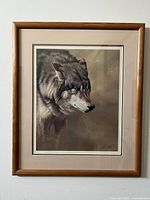 Framed artwork featuring realistic wolf portrait by Alan M. Hunt, signed print with double matting in wood frame shown hanging.