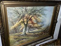 Framed watercolour painting showing vibrant trees in a natural landscape scene with a golden-yellow and green color palette.