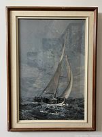Framed sailboat painting showing ocean, boat, sails and cloudy sky under glass.