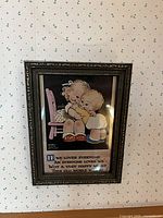 Photo of framed art print showing brother and sister hugging with quote beneath, hung on wallpapered wall.