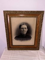 Full view of the charcoal portrait sketch in the carved ornate wooden frame showing the entire artwork and frame.