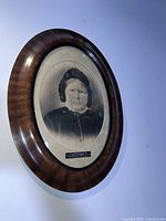 Framed charcoal sketch portrait of a woman, taken at an angle showing the frame and the artwork.