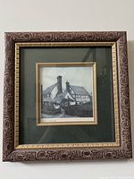 Framed etching photograph with ornate wood frame and gold inner border showing a traditional cottage with chimneys.