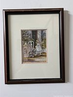 The framed art print by Trisha Romance features a young girl on a porch with a dog, potted plants, white chair, and window shutters. The photo captures the full piece including the dark wood frame and double matting.