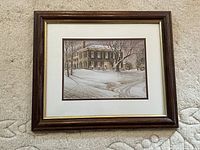 Framed signed print showing winter landscape scene with house and snow.