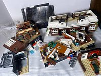 Spread of 2 LEGO toy buildings with scattered parts and instruction booklet in the background