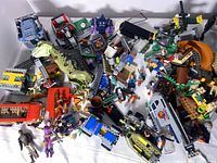 Overview photo showing assorted LEGO elements including dinosaur figure, minifigures, building parts and vehicle bases.