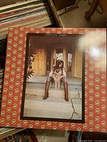 Close-up photo of Emmylou Harris Elite Hotel album cover with vinyl records stacked behind it.