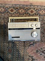 Top view of the SONY Model TFM-116L portable FM/AM radio showing the frequency display, tuning knobs, speaker grille, and extendable antenna.