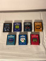 Seven boxed vintage Atari 2600 video games by Activision arranged on white surface.