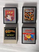 Four Atari 2600 game cartridges laid out on a white cloth, tagged: Taz, Mario Bros., Carnival, Ms. Pac-Man.