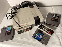 Front view of NES console with 2 controllers and 3 game cartridges laid out around it.