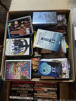 Box containing multiple DVDs and CDs from the 1990s/2000 movies with visible titles and cases.