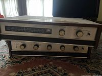 Front view of the Heathkit AA-22 amplifier and AJ-33a tuner stacked showing wood casing, metal front panels with various control knobs and AM/FM tuner scale