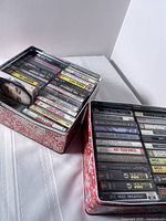 View of one metal tin filled with vintage cassette tapes in good condition, labels visible including MCA and London records.