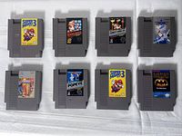 Top-down photo of eight vintage NES game cartridges arranged in two rows of four on a white surface, clearly showing game labels.