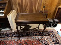 Full view of the restored antique mahogany games table from the front and side on patterned rug.