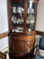 Full view of the Drexel curved mahogany corner china cabinet with contents inside showing glass doors and wooden lower cabinet