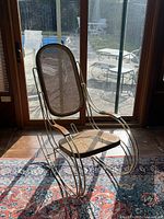 Angled front view showing brass frame, cane seat and back