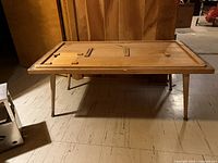 Full view of rustic Mid-Century Modern style coffee table made from pine and teak wood, showing table top with inset panels and angled legs.