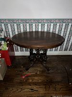 Front view of the oval walnut parlour table showing the wood grain top and carved base.