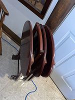 The set of four oval TV trays stacked on the stand showing side view and thickness.