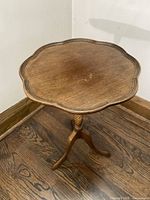 Full view of scalloped pie crust top of antique walnut end table showing wood grain and shape