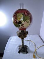 Front view of entire lamp showing painted globe, base and chimney