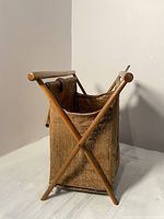 Angled front view of the vintage antique burlap sack book holder showing wooden handles and crossed wooden legs.