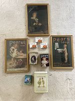 Full overview of lot showing framed prints, soap bars and advertising tins arranged on carpeted floor