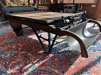 Side perspective showing wooden top, iron base, wheel and handle