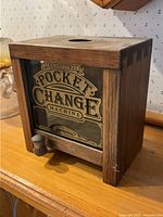 Front angle view showing the wooden construction, glass panel with lettering, and coin slot on top.