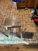 Photo showing two teak wood nesting step stools on tiled floor, one larger square top stool and one smaller rectangular stool.