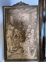 Full view of the rectangular needlepoint tapestry in ornate gold-tone carved frame showing aristocratic figures in period dress in an interior setting.