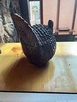 Photo of the rooster figurine from left side showing textured feather detail and tail.