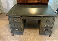 Front view of antique green metal military desk showing six drawers and flat top surface