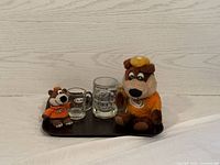 Photo of lot showing two A&W mascot bears, two A&W glass beer mugs, all on a dark brown serving tray, against a white wood plank background.