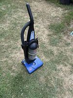 Full view of blue Bissell PowerForce bagless vacuum showing angled side with attached hose and handle.