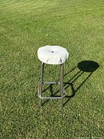 Photo of chrome base stool with white padded seat on grass showing overall condition and style.