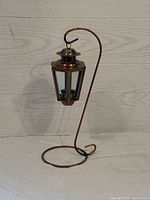 Full view of copper hanging candle holder on curved stand showing size and shape